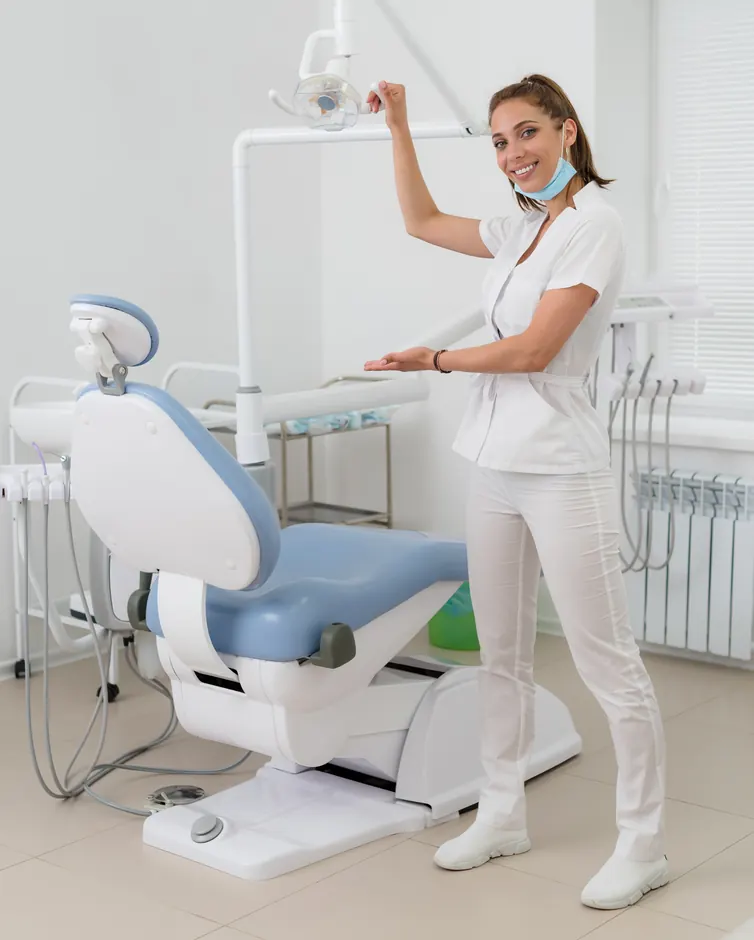 Dentist in a treatment room beside the dental chair
